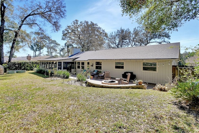 rear view of property with a fire pit, a patio, a lawn, and a sunroom