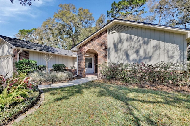 view of front of property with an attached garage, a front yard, and brick siding