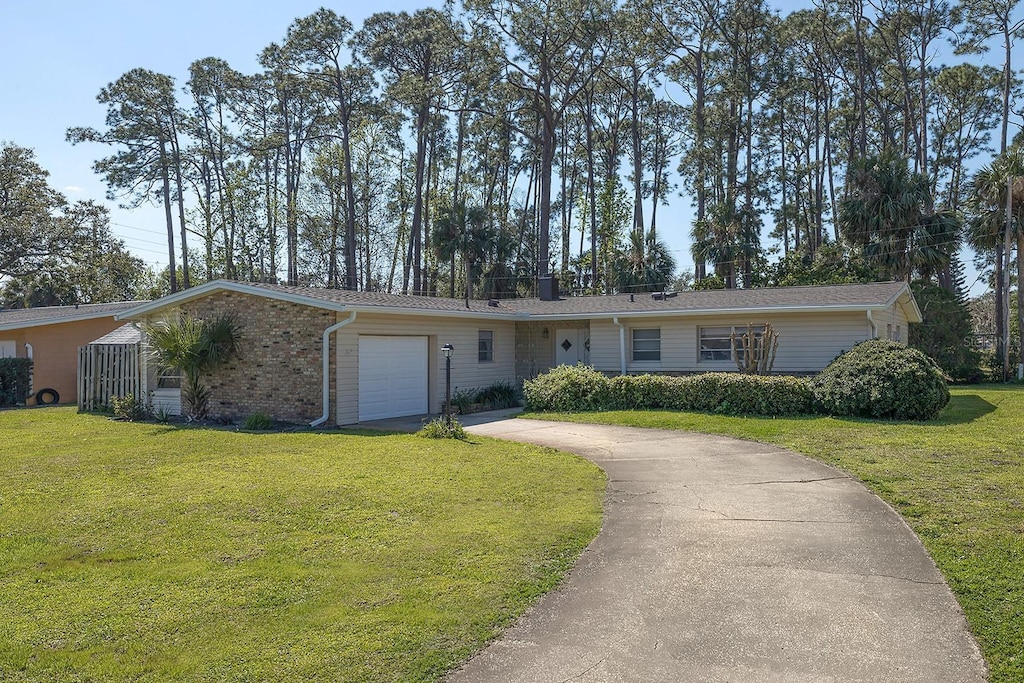 ranch-style house with brick siding, an attached garage, driveway, and a front lawn