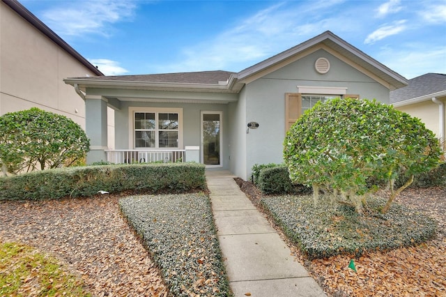 doorway to property with covered porch and stucco siding