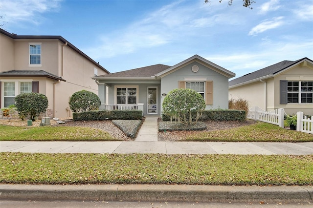 view of front of home with covered porch, fence, and stucco siding