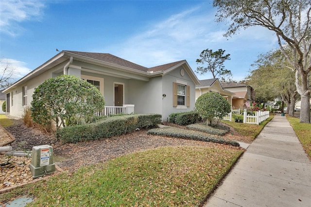 ranch-style home featuring roof with shingles, fence, a porch, and stucco siding