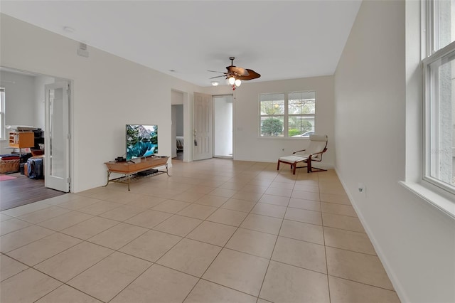 unfurnished room featuring light tile patterned flooring, a ceiling fan, and baseboards