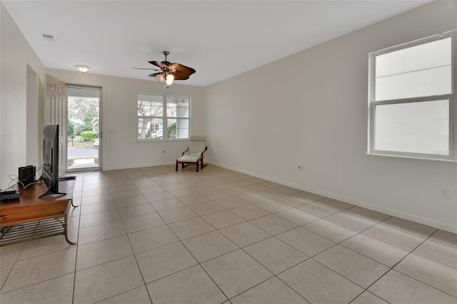 empty room featuring light tile patterned flooring, ceiling fan, and baseboards