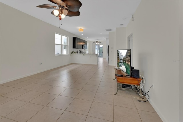 living room featuring light tile patterned floors, ceiling fan, visible vents, and baseboards