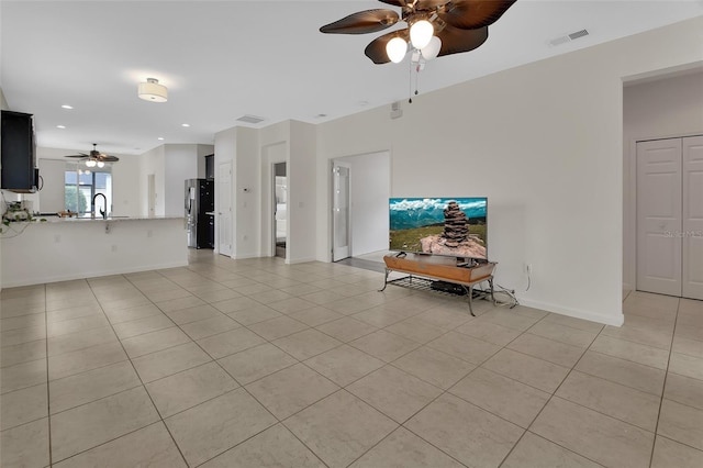 unfurnished living room featuring light tile patterned floors, baseboards, visible vents, and a sink