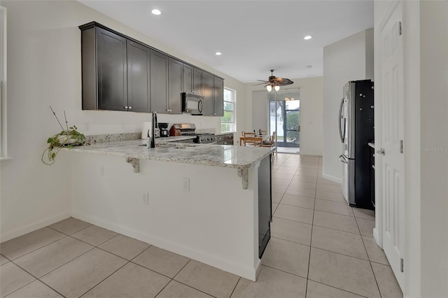 kitchen featuring light tile patterned floors, stainless steel appliances, a peninsula, and a sink