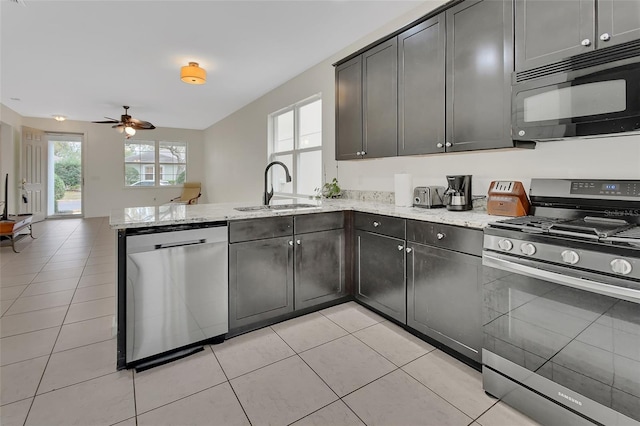 kitchen featuring a peninsula, appliances with stainless steel finishes, a sink, and a healthy amount of sunlight