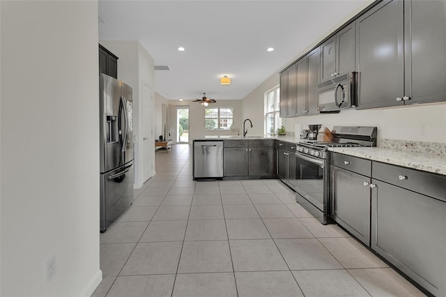 kitchen with light tile patterned floors, visible vents, a peninsula, stainless steel appliances, and a sink