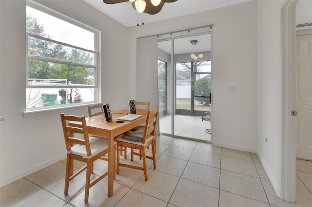 dining area featuring light tile patterned floors, a ceiling fan, and baseboards