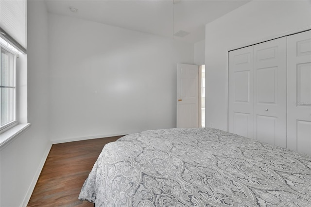 bedroom with baseboards, dark wood finished floors, and a closet