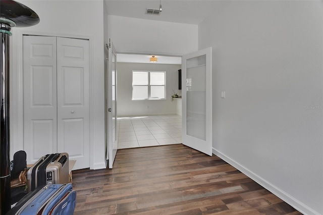 hall featuring wood finished floors, visible vents, and baseboards