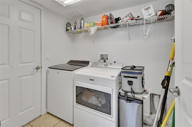 clothes washing area with laundry area, washing machine and dryer, and light tile patterned floors