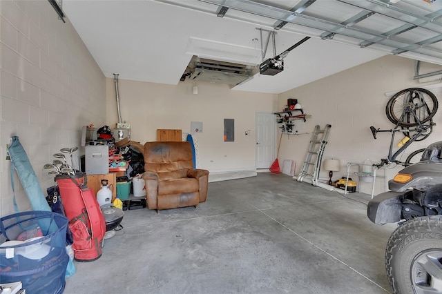 garage with concrete block wall, electric panel, and a garage door opener