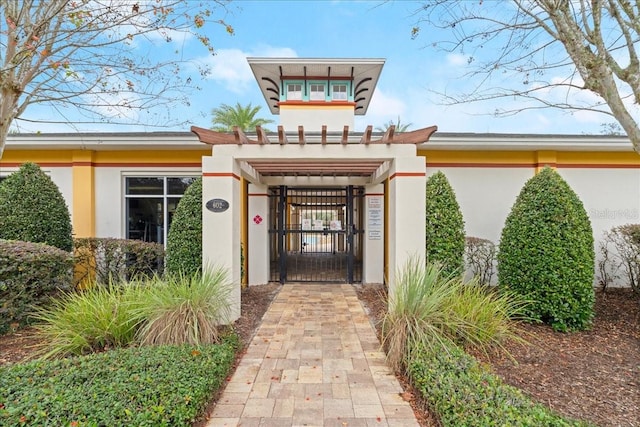 doorway to property with a pergola, a gate, and stucco siding