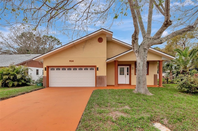 view of front of home featuring a garage, brick siding, concrete driveway, stucco siding, and a front yard