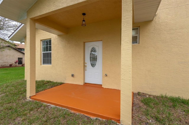 doorway to property featuring a yard and stucco siding