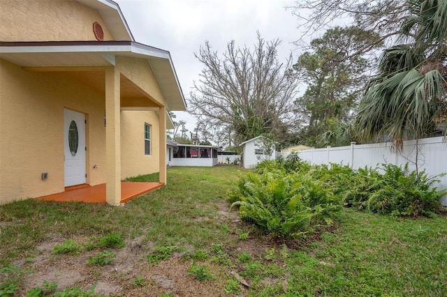 view of yard featuring an outbuilding, a storage unit, fence, and a sunroom