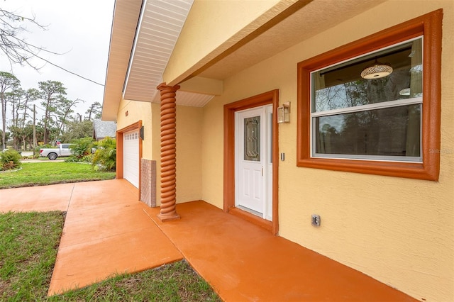 doorway to property featuring a garage and stucco siding