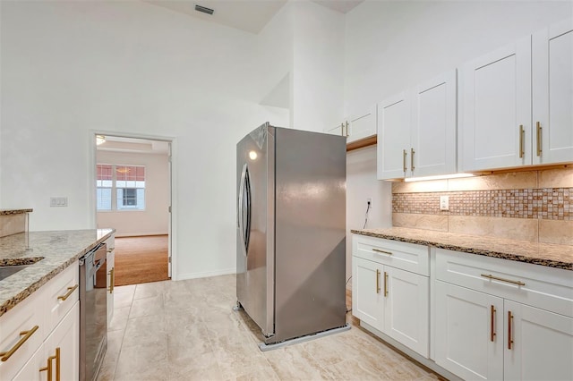 kitchen featuring stainless steel appliances, tasteful backsplash, a high ceiling, and light stone countertops