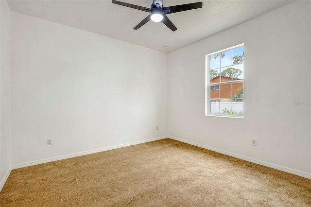 carpeted empty room featuring a ceiling fan and baseboards