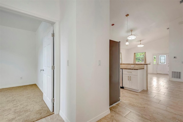 hall with visible vents, vaulted ceiling, and baseboards