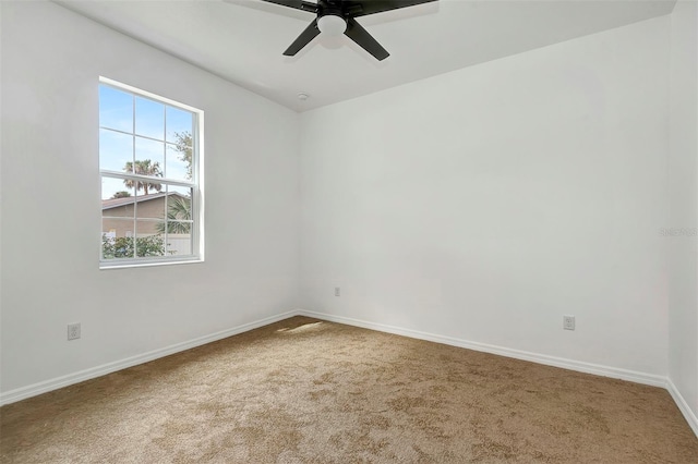 carpeted spare room with ceiling fan and baseboards