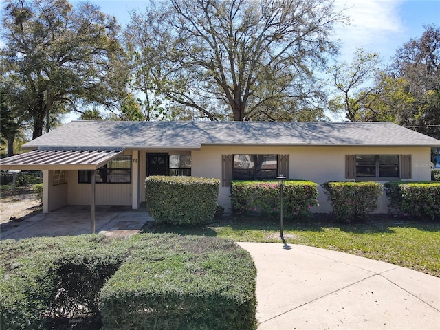 ranch-style home with metal roof, roof with shingles, a standing seam roof, a front yard, and stucco siding