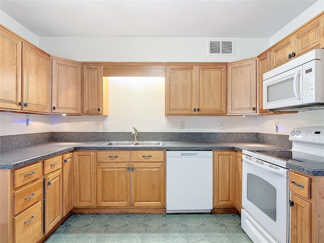 kitchen featuring dark countertops, white appliances, visible vents, and a sink