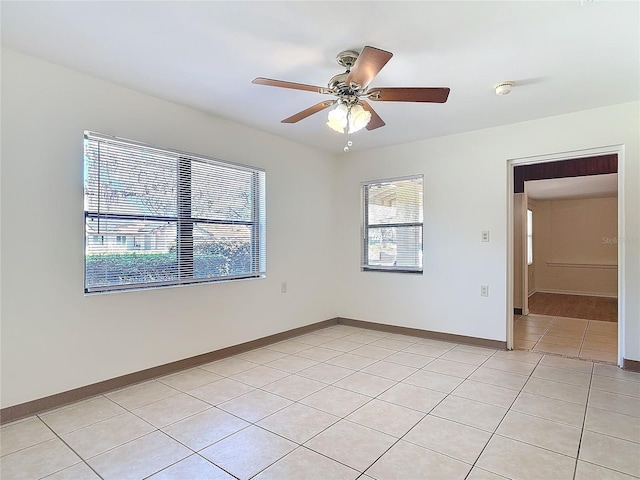 unfurnished room featuring light tile patterned flooring, a ceiling fan, and baseboards