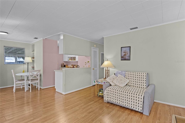 sitting room with visible vents, crown molding, baseboards, and wood finished floors