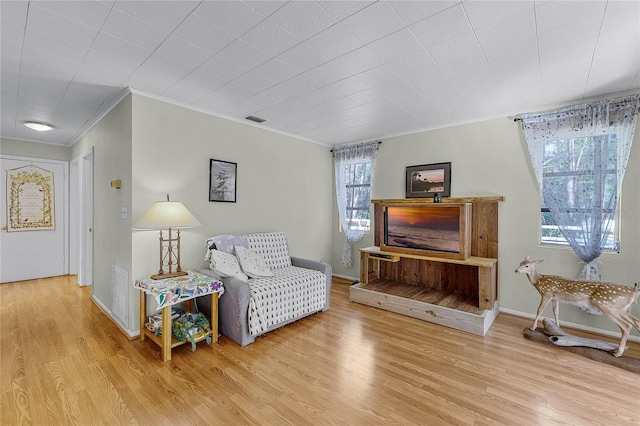 sitting room with ornamental molding, visible vents, baseboards, and wood finished floors