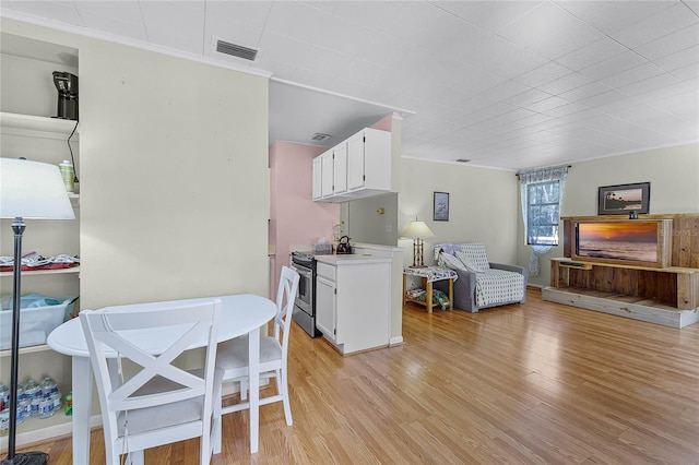 kitchen featuring stainless steel electric range oven, light wood-style floors, visible vents, and white cabinets