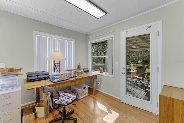 home office with crown molding, light wood-style flooring, and baseboards