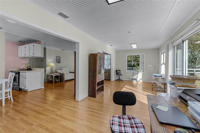 interior space featuring ornamental molding, light wood-type flooring, visible vents, and baseboards