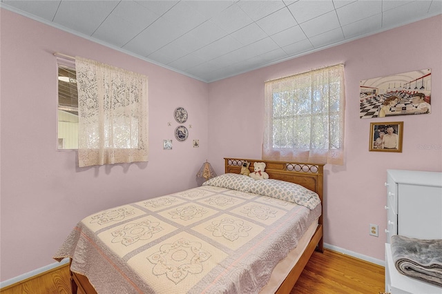 bedroom featuring ornamental molding, wood finished floors, and baseboards