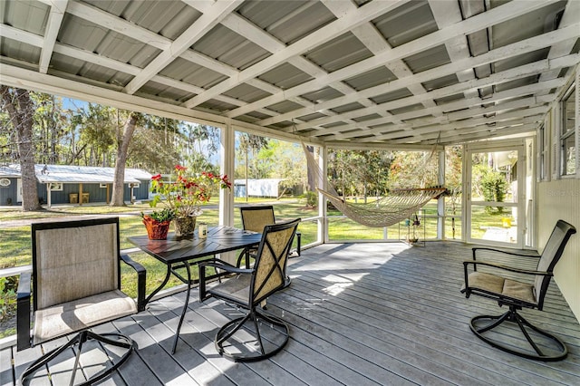 wooden terrace with outdoor dining area and a lawn