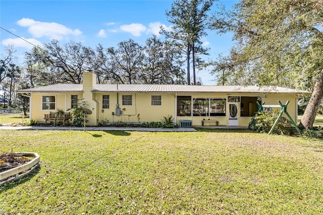 ranch-style home with a chimney, central AC unit, metal roof, and a front yard