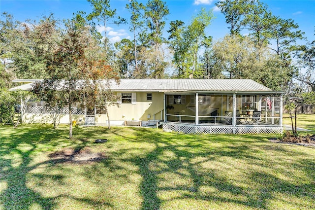 rear view of house with metal roof, a yard, and a sunroom