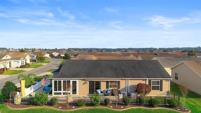 back of property featuring a shingled roof, a residential view, and fence