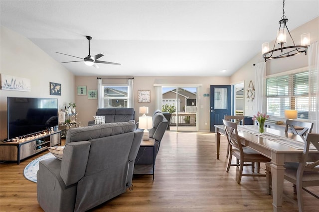 living room featuring vaulted ceiling, wood finished floors, and ceiling fan with notable chandelier