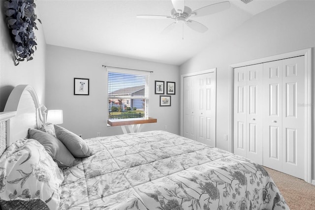 carpeted bedroom featuring multiple closets, vaulted ceiling, and a ceiling fan