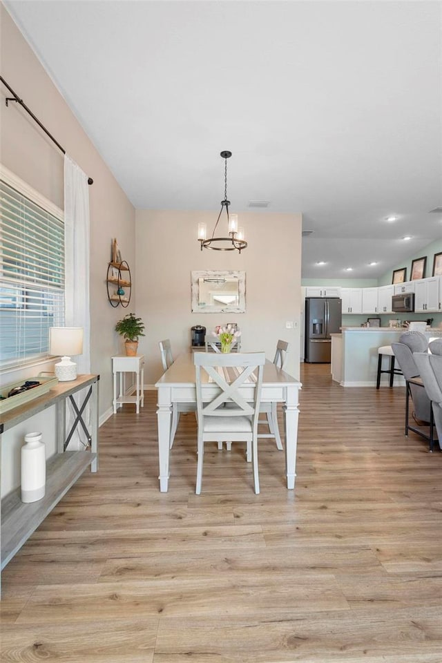 dining area featuring light wood-style floors, recessed lighting, a notable chandelier, and baseboards