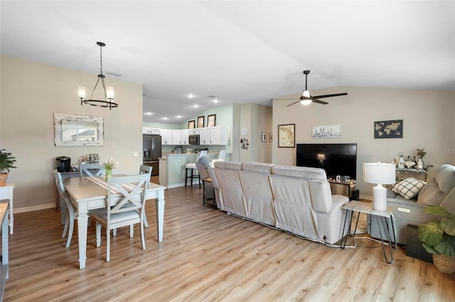 living area with lofted ceiling, baseboards, light wood finished floors, and ceiling fan with notable chandelier