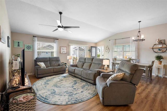 living room featuring lofted ceiling, a textured ceiling, ceiling fan with notable chandelier, and wood finished floors