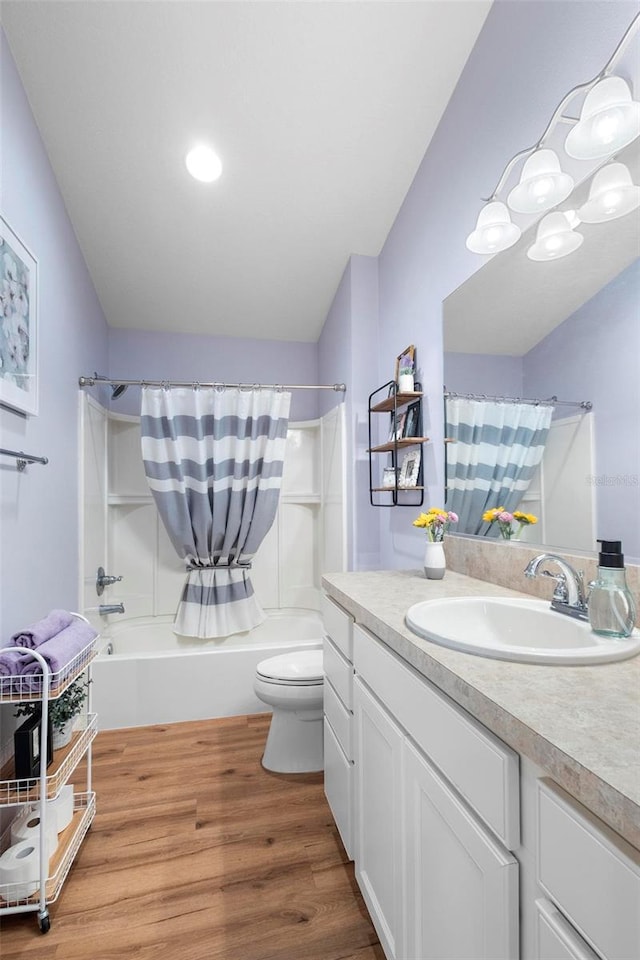 bathroom with toilet, shower / bath combo with shower curtain, wood finished floors, and vanity