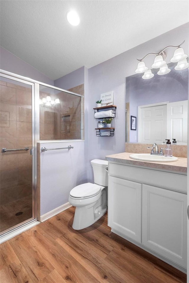 bathroom featuring a stall shower, vanity, toilet, and wood finished floors