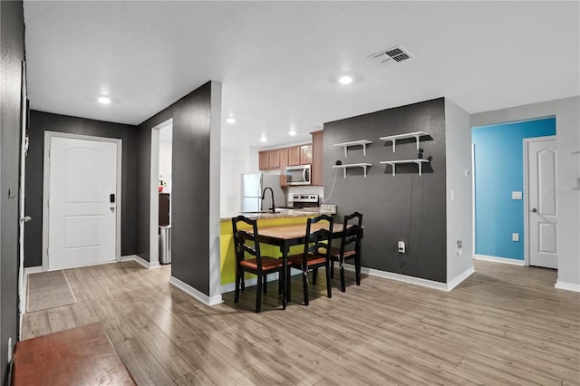 dining space featuring light wood finished floors, recessed lighting, visible vents, and baseboards