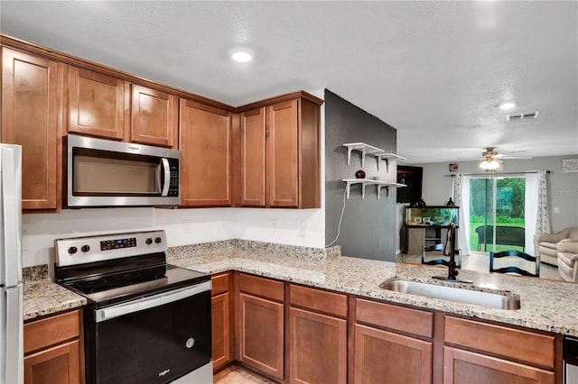 kitchen featuring light stone counters, visible vents, stainless steel appliances, and a sink