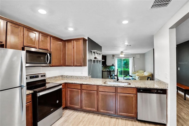 kitchen featuring a sink, visible vents, appliances with stainless steel finishes, light wood-type flooring, and light stone countertops